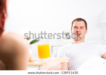 woman brought her boyfriend breakfast in bed, holding a tray of juice and breakfast