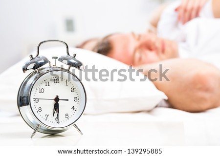 close-up alarm clock next to the sleeping people