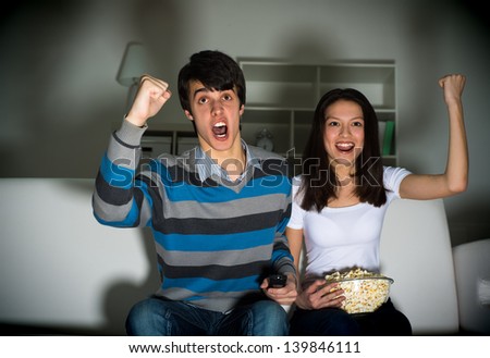 couple watching TV on the couch, sports fans