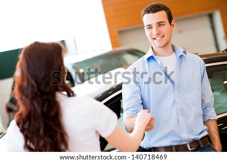 man shaking hands with car salesman, buying a new car