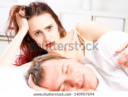 woman sleeping next to her husband in bed, relationship problems people
