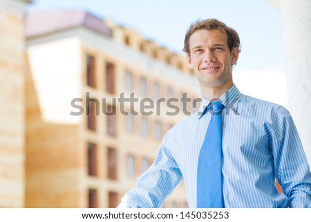 successful young businessman smiling, standing on the balcony