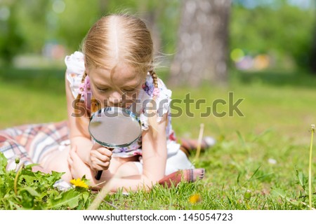 girl in the park with a magnifying glass considers plants