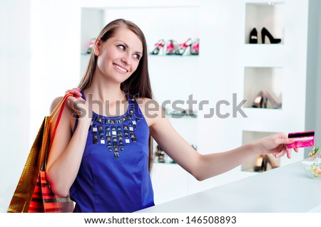 Young woman at shopping mall checkout counter paying through credit card