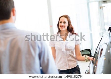 cute woman chooses a new car in the lounge car sales