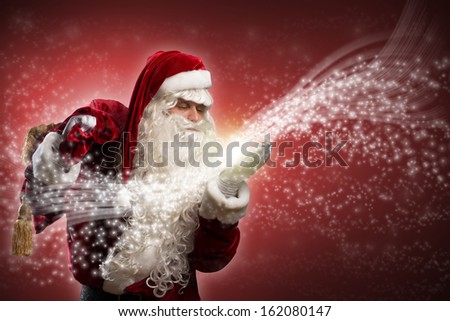 santa claus blows with hands magic sparks holds on shoulder bag with Christmas presents