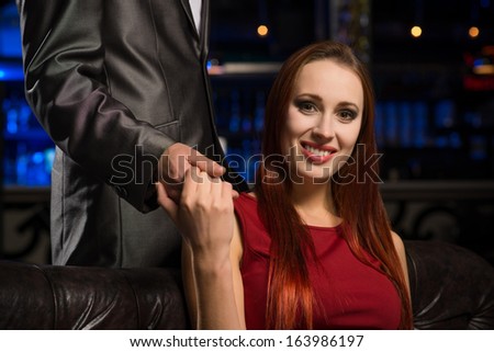 portrait of a respectable woman sitting on a couch and holding the hand of a man
