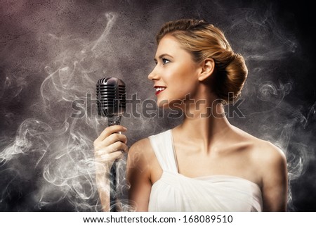 beautiful blonde woman singer with a microphone, eyes opened, around smoke