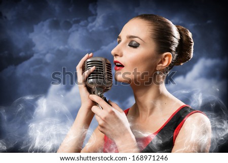 beautiful blonde woman singer with a microphone, eyes closed, around smoke