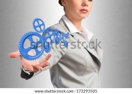 business woman holds up a mechanism of gears, concept of ready solutions