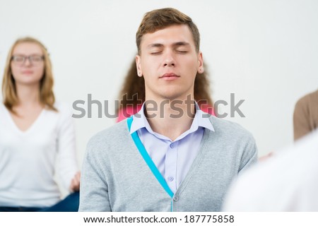 young man, meditating with closed eyes, group meditation
