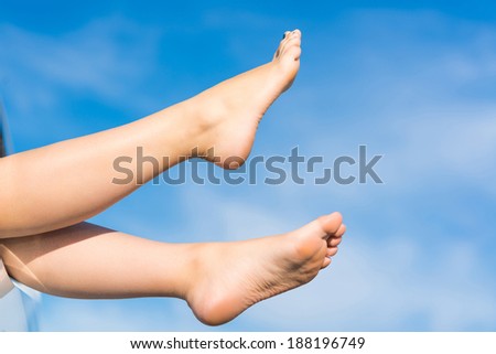 feet of a young girl from the window of a car on a background of blue sky