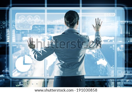 businesswoman working with modern virtual technologies, stands back, hands touching the screen