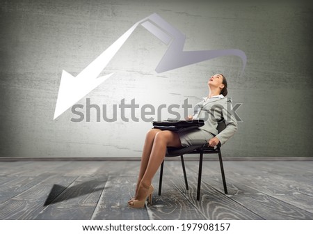 Young troubled businesswoman sitting on chair and looking on arrow above