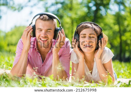 Young couple in summer park listening music
