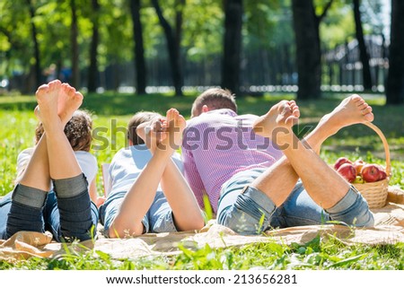 Young happy family lying in park barefoot