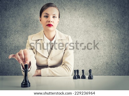 Serious pretty woman sitting and playing chess