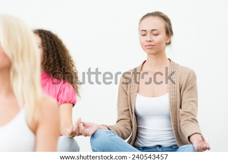 attractive young woman, meditating with closed eyes, group meditation