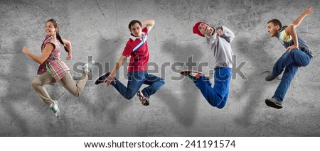 Group of dancers in jump on cement background