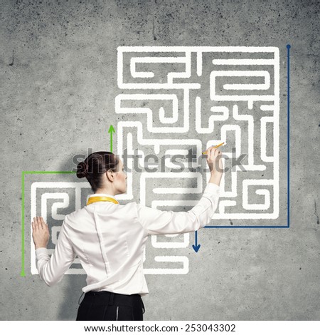 Back view of businesswoman drawing labyrinth on wall