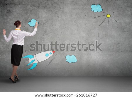 Rear view of businesswoman drawing rocket on wall