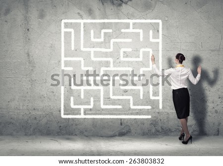 business woman draws a maze on the wall, the concept of finding a solution in business