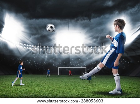 Excited boy football player at stadium kicking ball