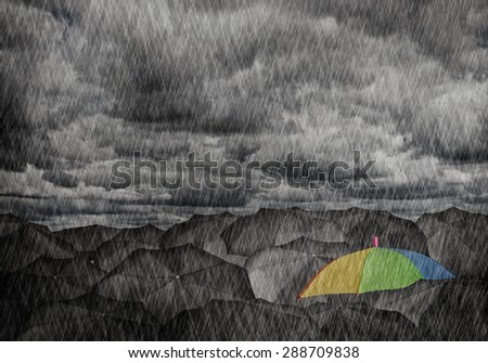 Conceptual image with colorful umbrella among many black ones