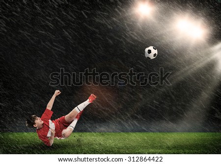 Kid boy kicking soccer ball at stadium field