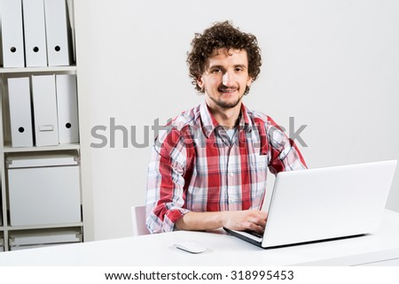 Young man in checked shirt typing on his notebook