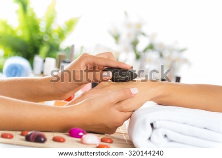 Woman in salon receiving manicure by nail beautician