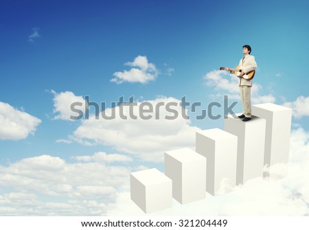 Full length of young businessman in suit standing on graph bars with guitar