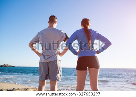 Young active couple of joggers on beach taking breath