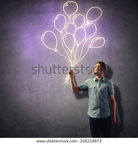 Young handsome man in casual with drawn bunch of balloons in hand