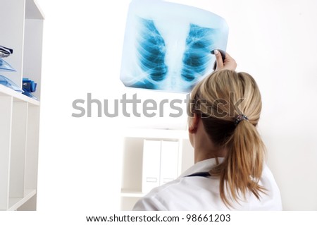 woman doctor looks at x-ray film, shot from behind