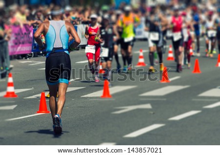 Photo of a marathon competition during an ironman. Use of tilt shift lens for selective focus on the man in the foreground