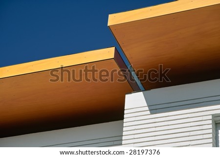 Geomerical composition of an orange colored roof of a modern white house against a deep blue sky