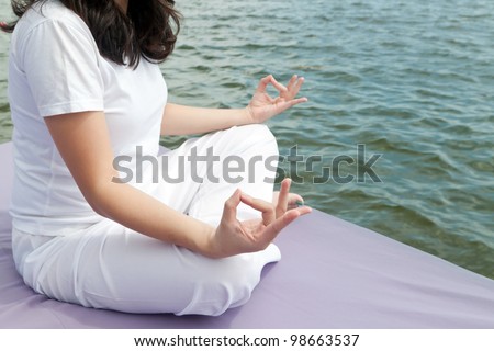 Attractive young asian woman practicing yoga meditation at sunrise by the ocean