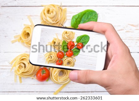 Hands taking photo pasta with smartphone.