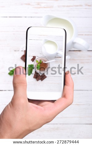 Hands taking photo milkshake with smartphone.