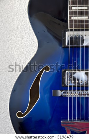 Left side detail of blue jazz guitar with strings and f-hole