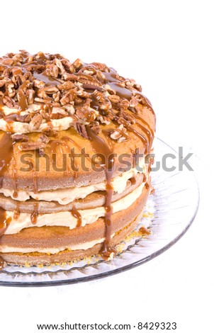 sweet pumpkin cake dessert with cream filling and pecans on top drizzled with caramel topping on clear plate