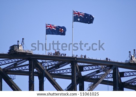 groups of tourists on top of sydney harbor bridge with two australian flags