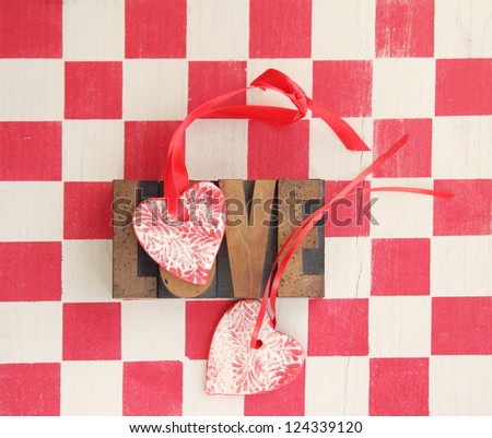 two handmade heart ornaments with the word \'love\' against a red checked background