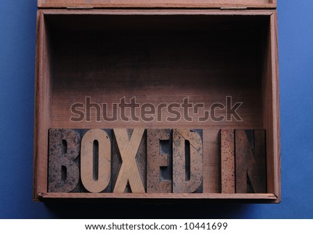the phrase \'boxed in\' in wood type inside a wood box