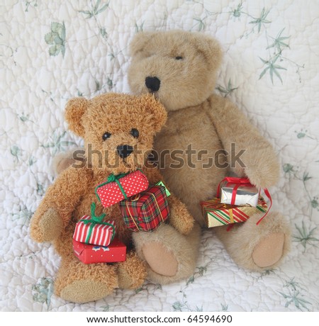 two toy bears with brightly wrapped Christmas gifts against a quilt