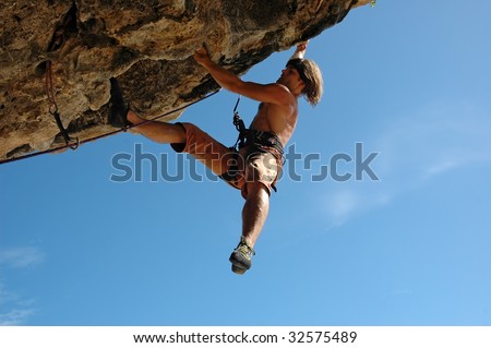 Adult climbing hard overhanging rock.
