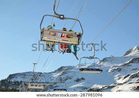 People are being transported with a chair lift up the snowy slope in the ski resort