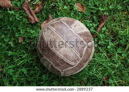 Old brown volleyball ball on green grass