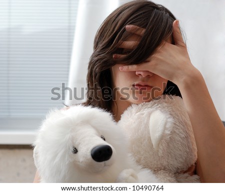 Portrait of teenage girl with teddy bear, face hid with hand